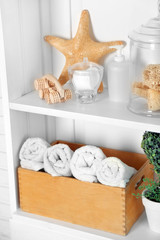 Fototapeta na wymiar Bathroom set with towels, starfish and sponges on a shelf in light interior