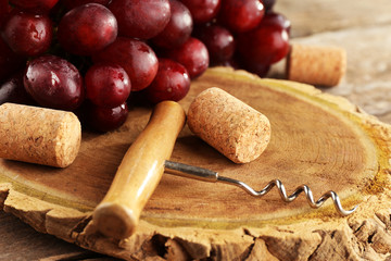 Wine corks and tailspin with bunch of grapes on wooden background