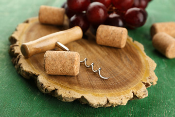 Wine corks and tailspin with bunch of grapes on wooden background