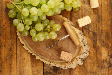 Wine corks and tailspin with bunch of grapes on wooden background