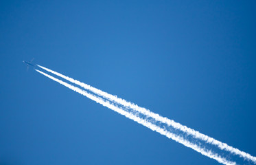 ein Flugzeug mit Kondensstreifen zieht am Himmel seine Bahn