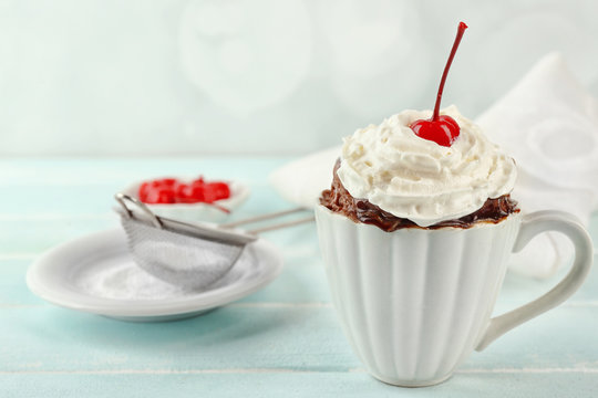 Chocolate mug cake with cream and cherry on a table