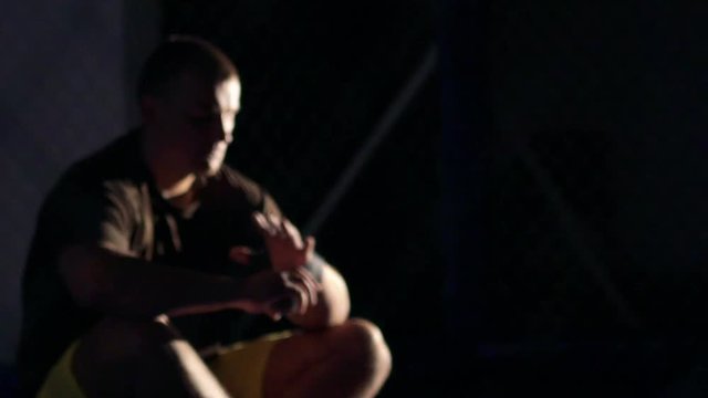 Young boxer wrapping bandages on his hand before fight