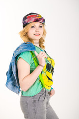 Portrait of young girl with a phone. Trendy Casual Fashion Outfit in Spring. Beautiful girl in a bright youth clothing, gay t-shirt, cap and suspenders for jeans. 

