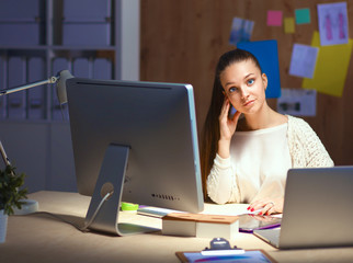 Young woman working in office, sitting at desk and talk on the phone