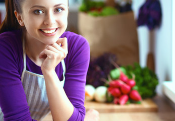 Young woman standing in her kitchen near desk