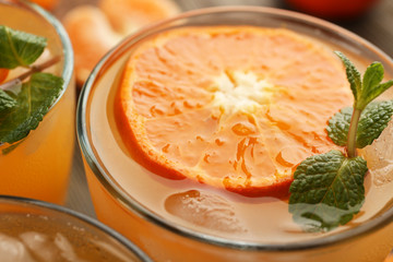 Tangerine cocktail with sliced mandarins, ice, mint, served on a wooden table, close up