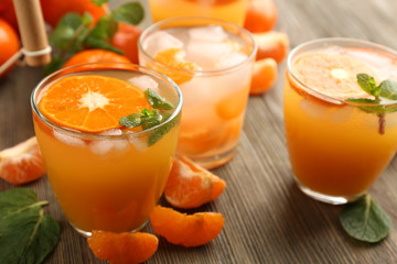 Tangerine cocktails with sliced mandarins, ice, mint on a wooden table, close up