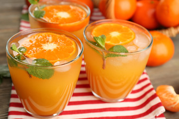 Delicious tangerine cocktails with sliced mandarins, ice and mint on a striped napkin, top view