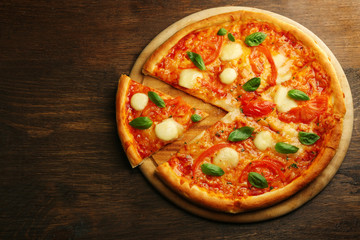 Sliced Margherita pizza on wooden background