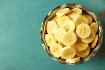 Banana slices in bowl on blue wooden background