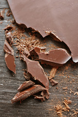 Pieces of chocolate on black wooden background, close up