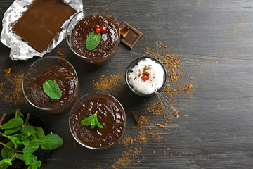 Glass cups of chocolate dessert with fresh mint and frothed milk on black wooden table