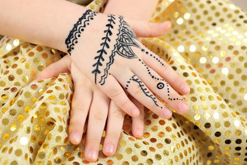 Henna ornaments on girl's hand on color cloth background
