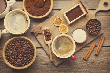 Cups of coffee with spices on wooden table, top view