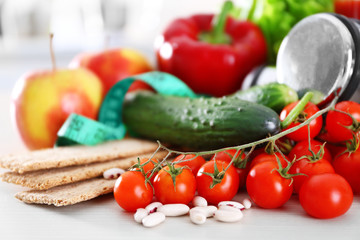 Set of fresh fruits and vegetables with dumbbells on wooden table closeup