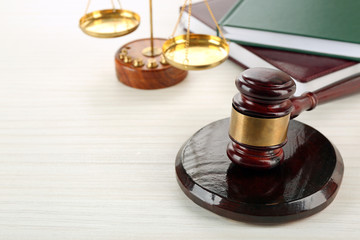 Gavel with books and scales on wooden background