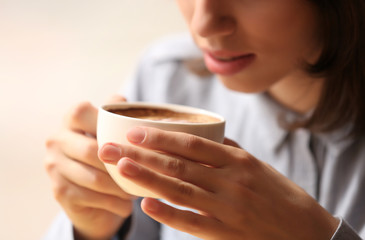 Young woman in cafe holding cup of coffee