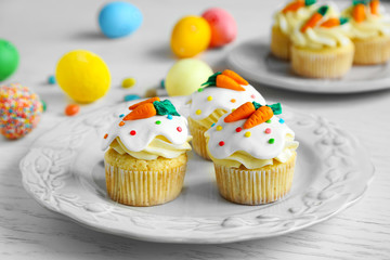 Plate with Easter cupcakes and eggs on wooden table