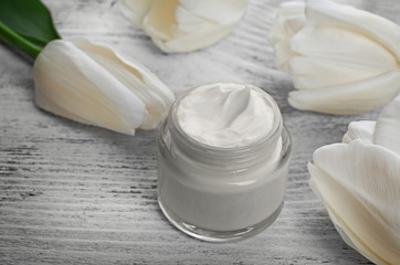 Fototapeta na wymiar Cosmetic cream with tulips on white wooden background