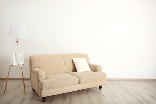 Beige couch and lamp on white wall background