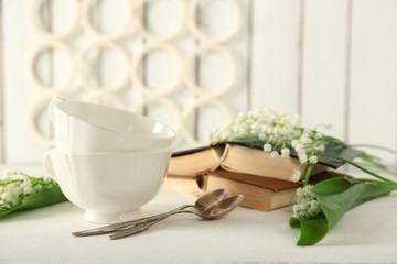 Porcelain cups with books and flowers on table