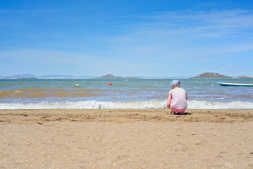Fototapeta na wymiar Small girl playing on the Mar Menor beach
