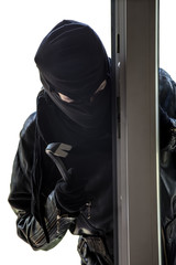 ein Einbrecher mit Maske dringt in ein Gebäude ein