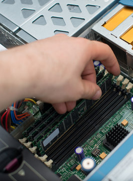 Computer technician installing RAM memory into motherboard.