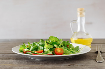 plate of fresh salad with carafe of oil