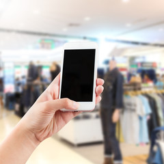 Close up female hand using smartphone in a market or department