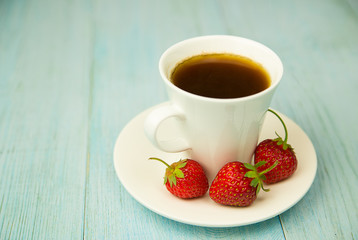 A cup with a drink and a strawberry on a blue