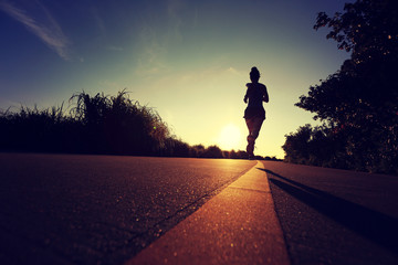 young fitness woman runner running on sunrise road