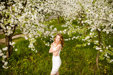 Spring beautiful girl, blonde, standing in a blooming Apple orchard .