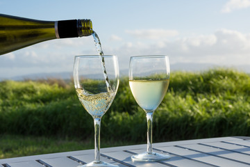 Pouring white wine into two glasses at the beach 