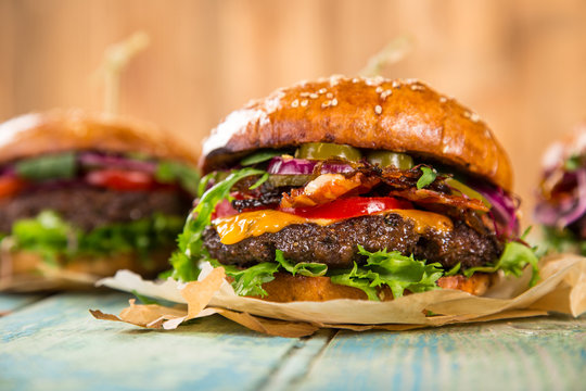 Tasty burgers on wooden table.