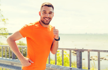 smiling young man running at summer seaside