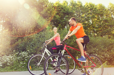 Obraz na płótnie Canvas happy couple riding bicycle outdoors
