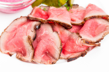 Sliced roast beef with pickles.