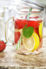 Detox Infused water with lemon, strawberry and mint on wooden background