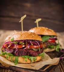Tasty vegetarian beet burgers on wooden table.