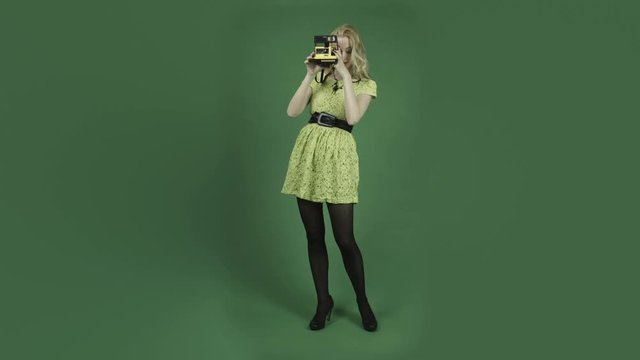 caucasian woman in yellow dress isolated on chroma green screen background polaroid camera