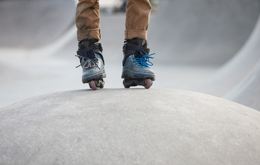 Feet of aggressive inline rollerblader on outdoor skatepark