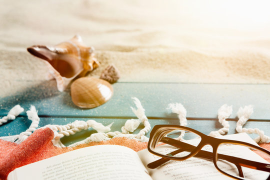 Buch und Brille an einem Sandstrand