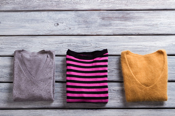 Folded v-neck sweatshirts. Garments on gray wooden background. Top quality items in showroom....