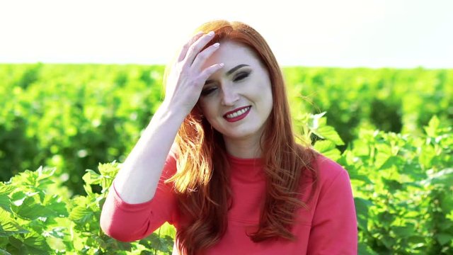 Portrait of happy girl smiling and touching hair n the green wheat field. Slowly