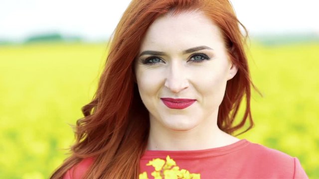 Happy girl face smiling on camera with bouquet of rape blossom. Slow motion