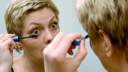 Pretty woman applying eyelashes mascara makeup