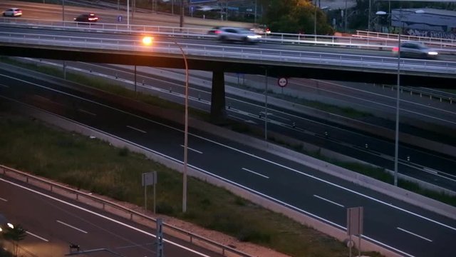 Road traffic scene in the dusk, with bridge in side view, and cars moving in different directions and levels, of entry and exit of Barcelona.time lapse.