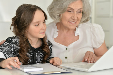 little girl making homework with granny